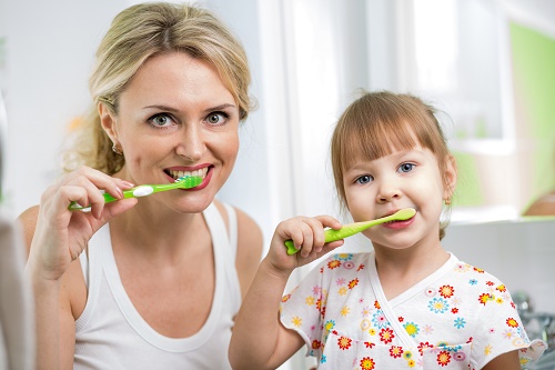 mother and child daughter brushing teeth in bathroom